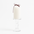 Vela decorativa blanca con diseño acanalado y lazo rojo