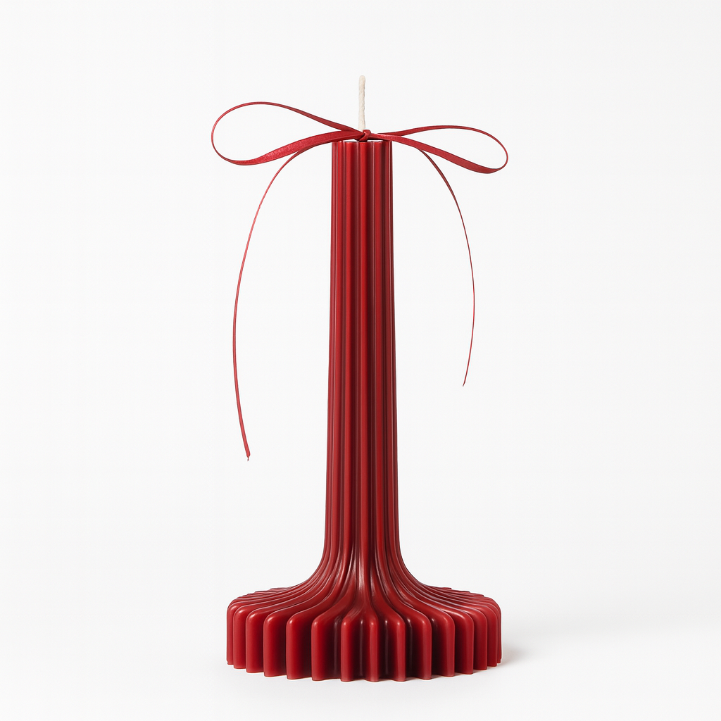 Vela decorativa roja con diseño vertical acanalado y lazo rojo.